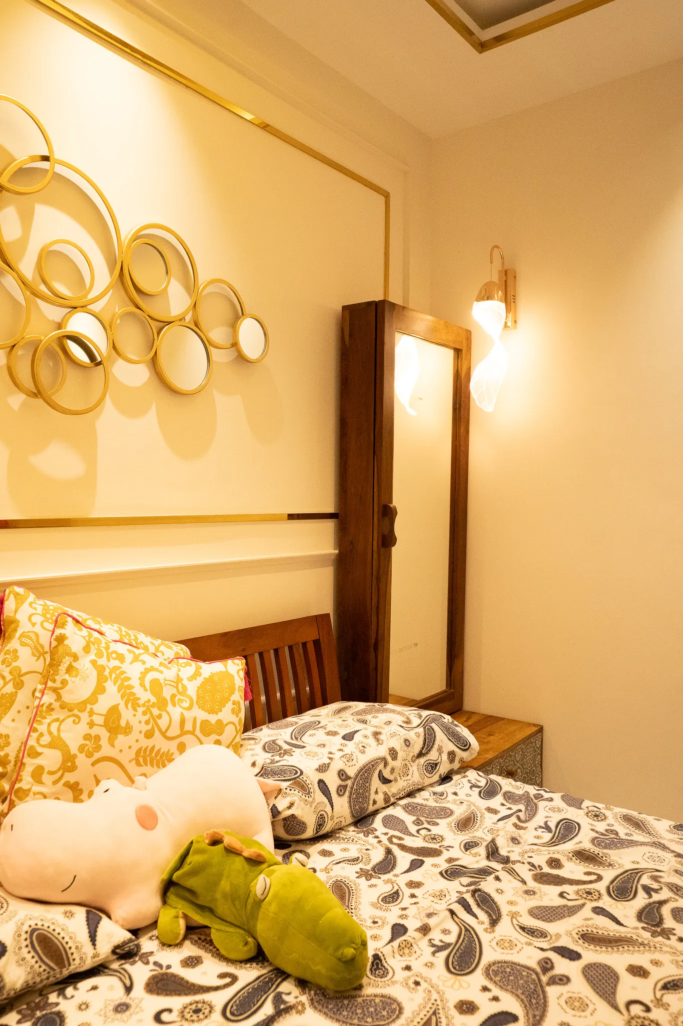 Bed beside gold disc wall art and dresser mirror — Divyarjuna